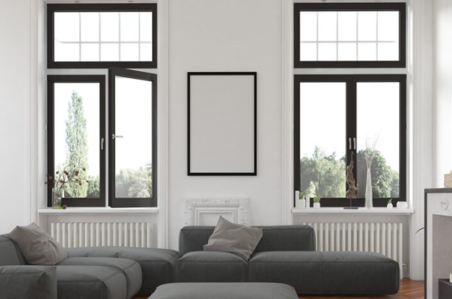 sala de una casa con dos ventanas en la pared de fondo. y algunos muebles grises y decoración. Carpintería de aluminio en Alcorcón